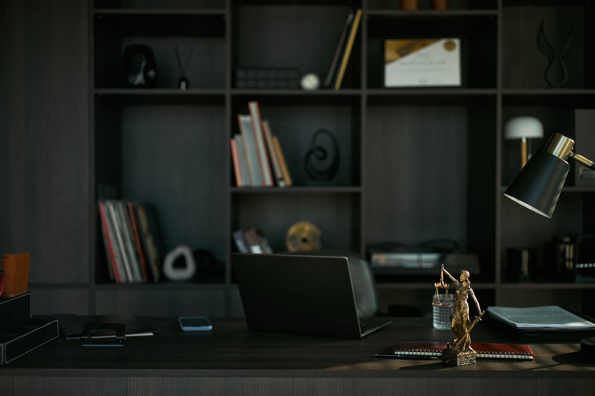 Lawyer's office desk with legal files and a Lady Justice statue, no people