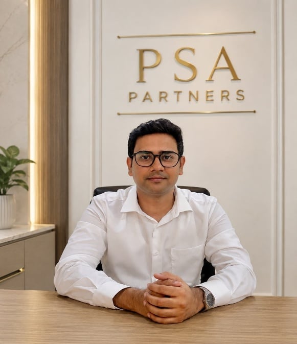 Man in white shirt sitting at desk with PSA Partners logo on wall behind him
