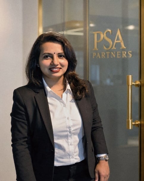 Professional woman in black blazer and white shirt standing in front of PSA Partners office entrance